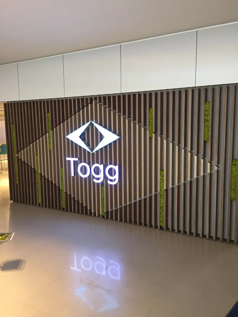 Togg Ankara alanında aydınlatmalı logo ve yeşil şeritli duvarın yakın görünümü